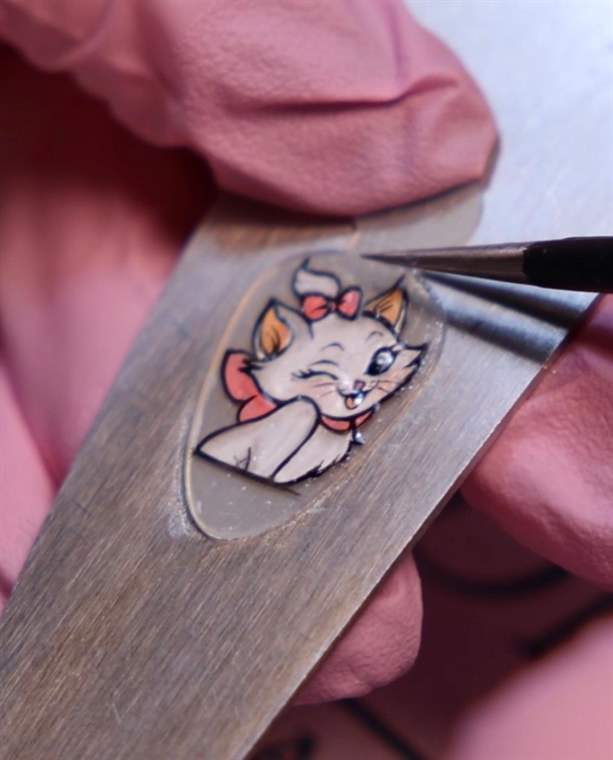 Pisica Marie pictată ca sticker, încă pe spatulă, lângă vârful pensulei
